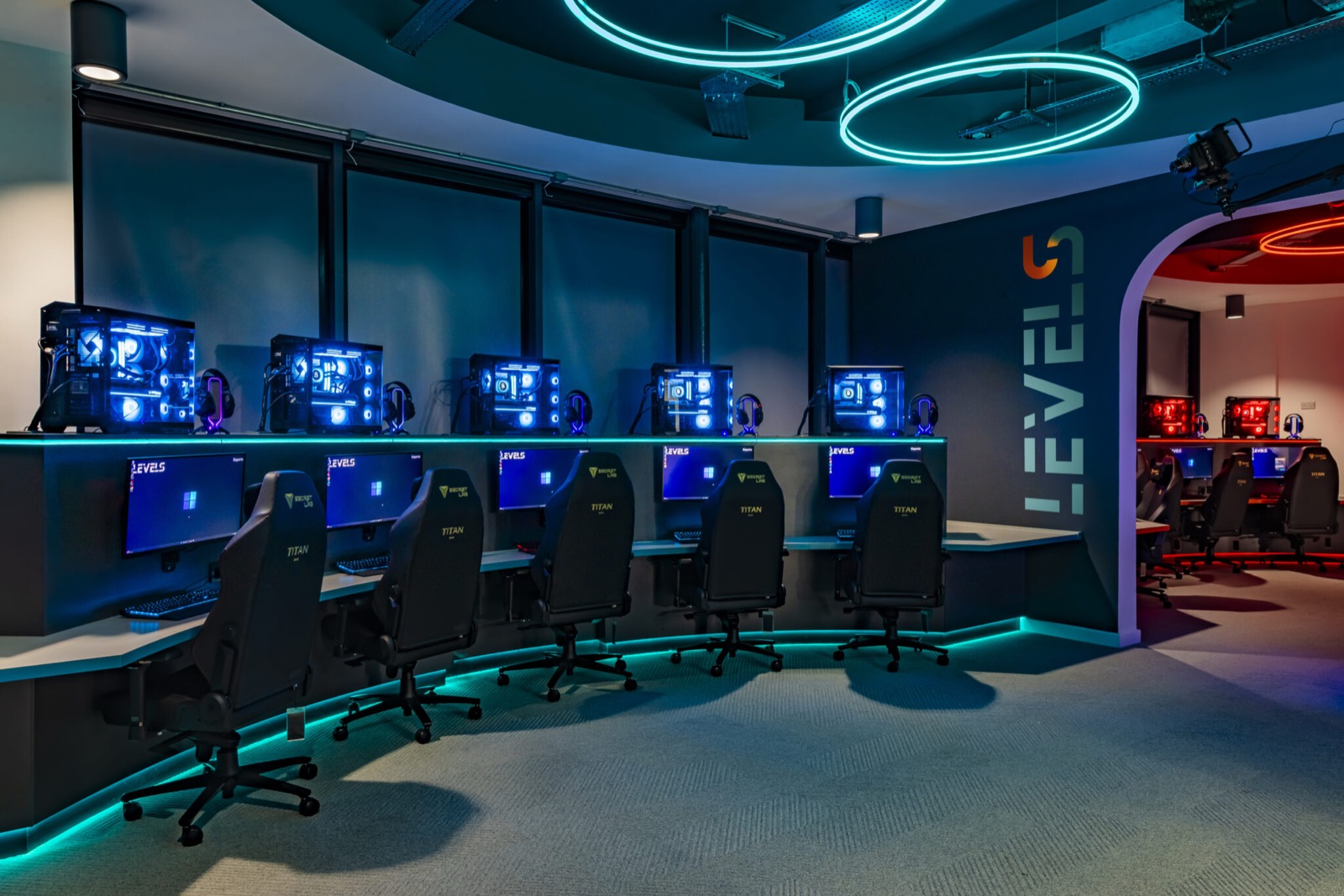 Rows of gaming PCs and chairs lit in blue inside the LEVELS esports arena