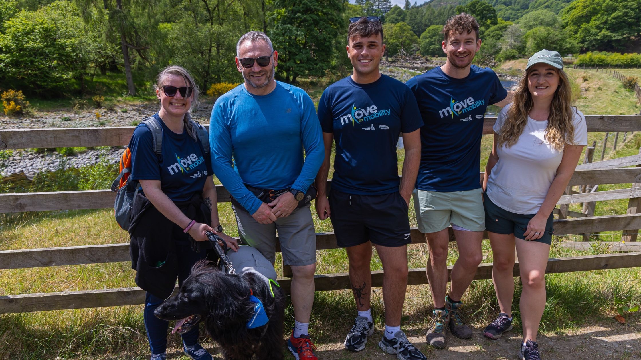 Walkers in Move for Mobility T-shirts, with a dog, beside a river in the Lake District